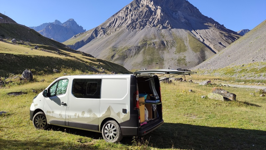 paysage de montagne avec van gris et covering vert dessus en face de la montage et ciel bleu 